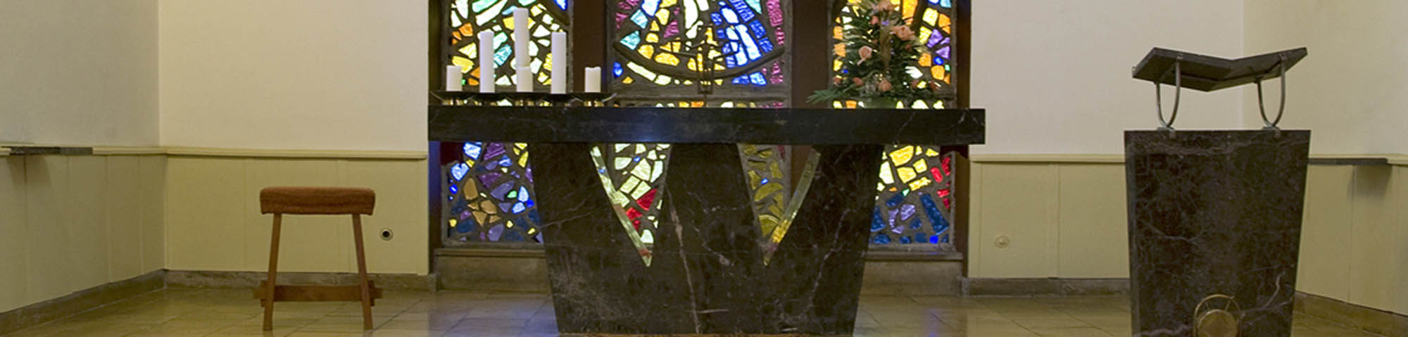 Altartisch der Marienkirche Markranstädt. Im Hintergrund sind bunte Glasfenster zu sehen.