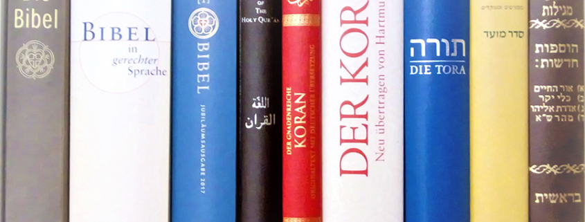 Bibel, Koran und Tora etc. auf einem Bücherbrett nebeneinander